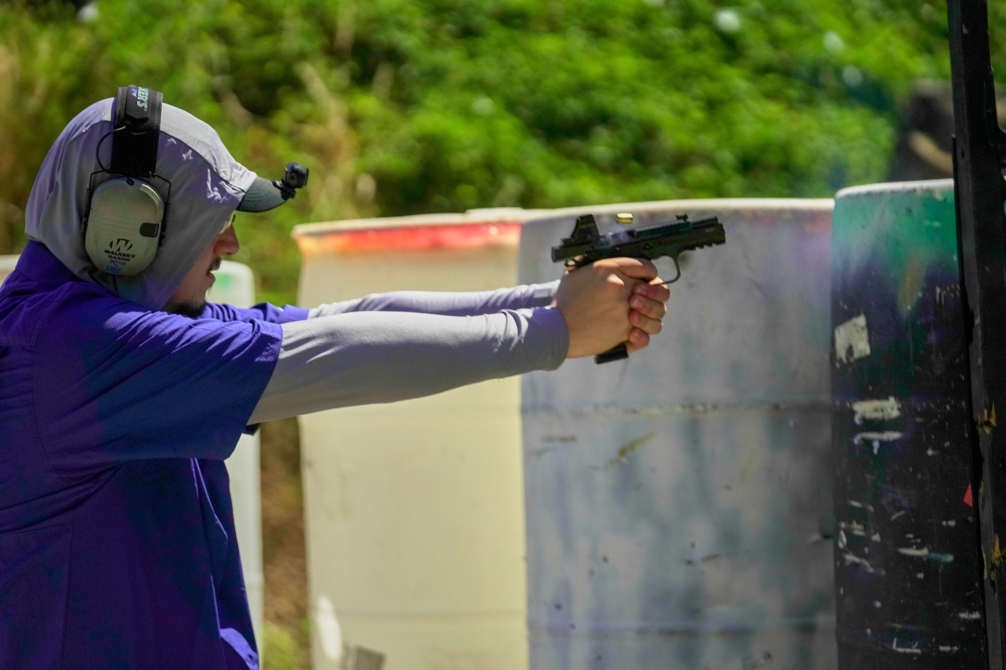 IDPA competitor firing with a red dot sight, side profile